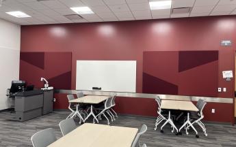 two tables with four chairs each and a whiteboard