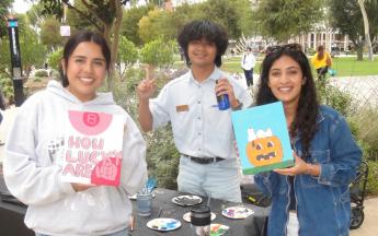three students holding up their paintings and posing