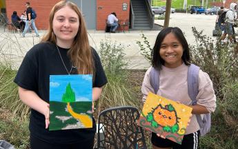 students posing and holding up their painting