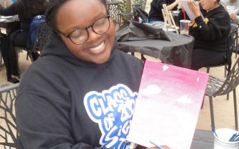 student smiling and holding up their painting