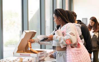 Student picking up a slice of pizza 