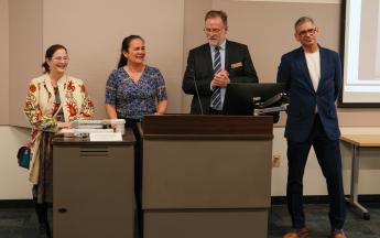 four people standing behind a podium