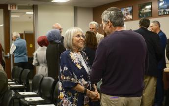 two people talking in foreground surrounded by other people