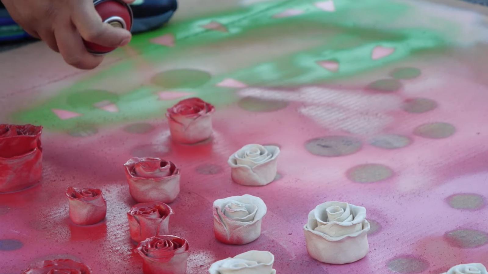 Still image of artist Patrick Martinez working on spray painting sculptural roses taken from Art Encounter studio visit educational video series available on Kleefeld Contemporary YouTube