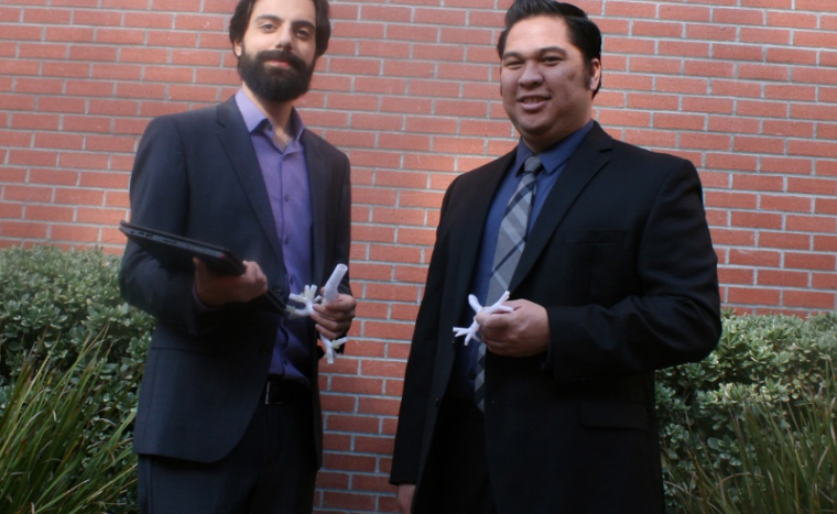 two men showing their prototype from their startup in business suits