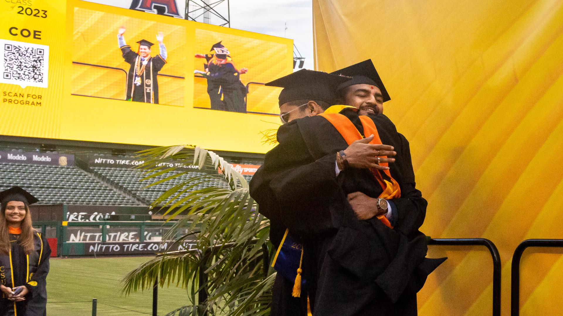 two students hug at graudation