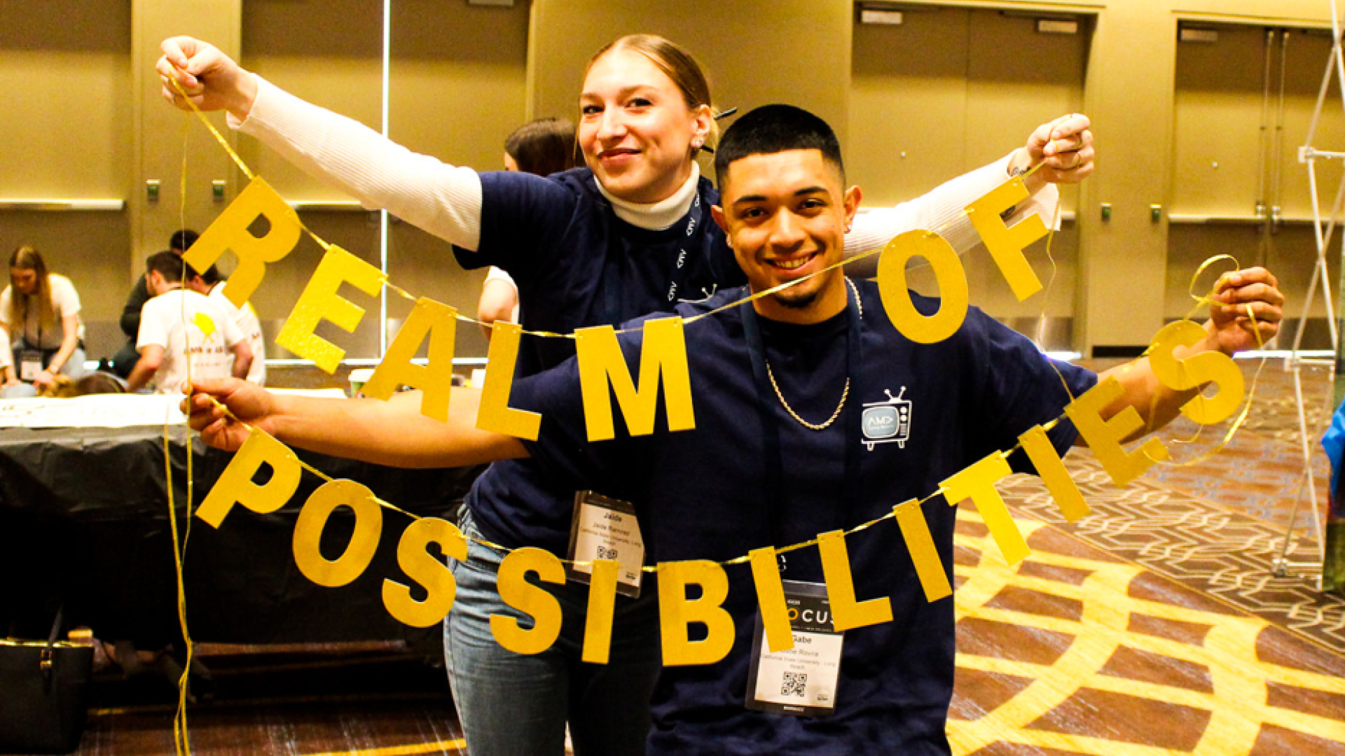 two students holding up a sign says Realm of Possibilities