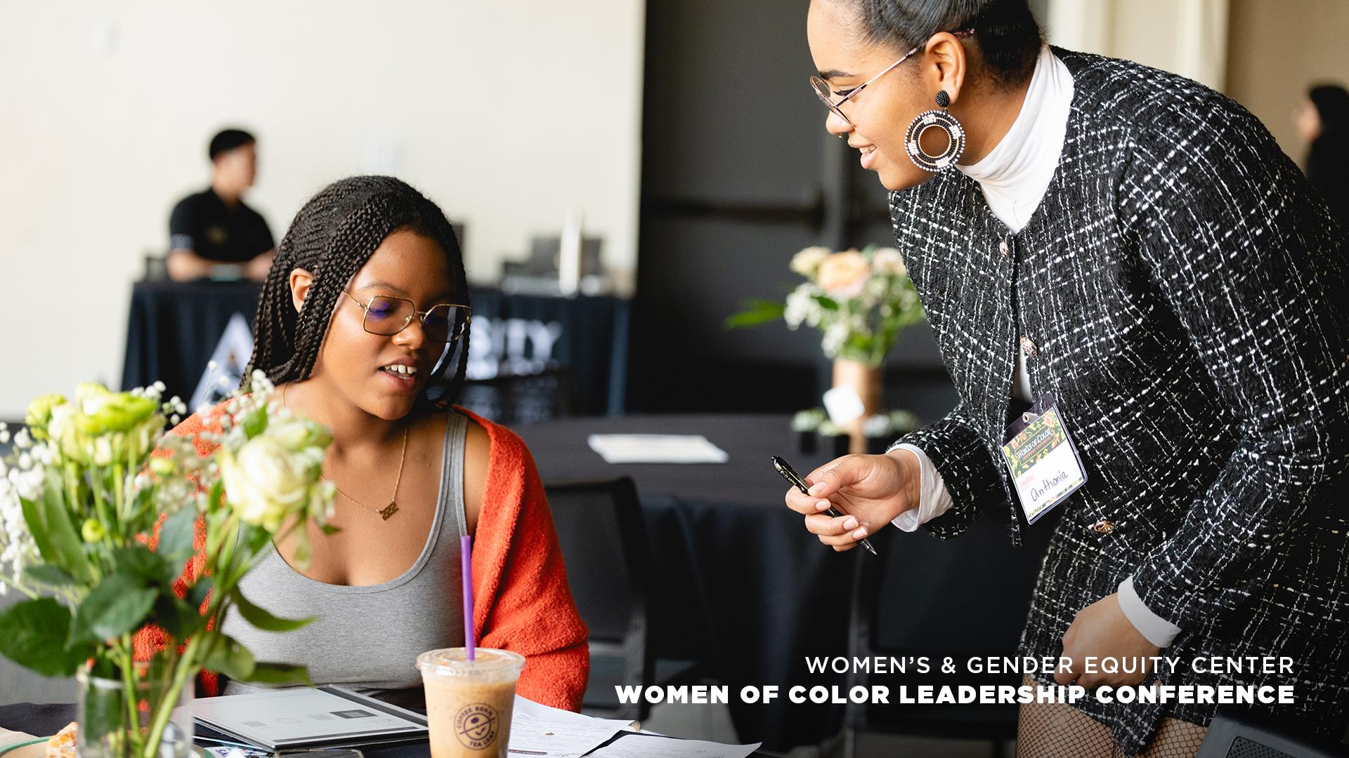 Two women discussing documents at leadership conference table.