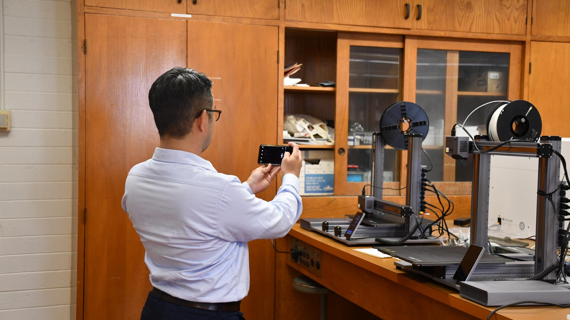 Man taking photo of state of the art equipment in an instructional lab