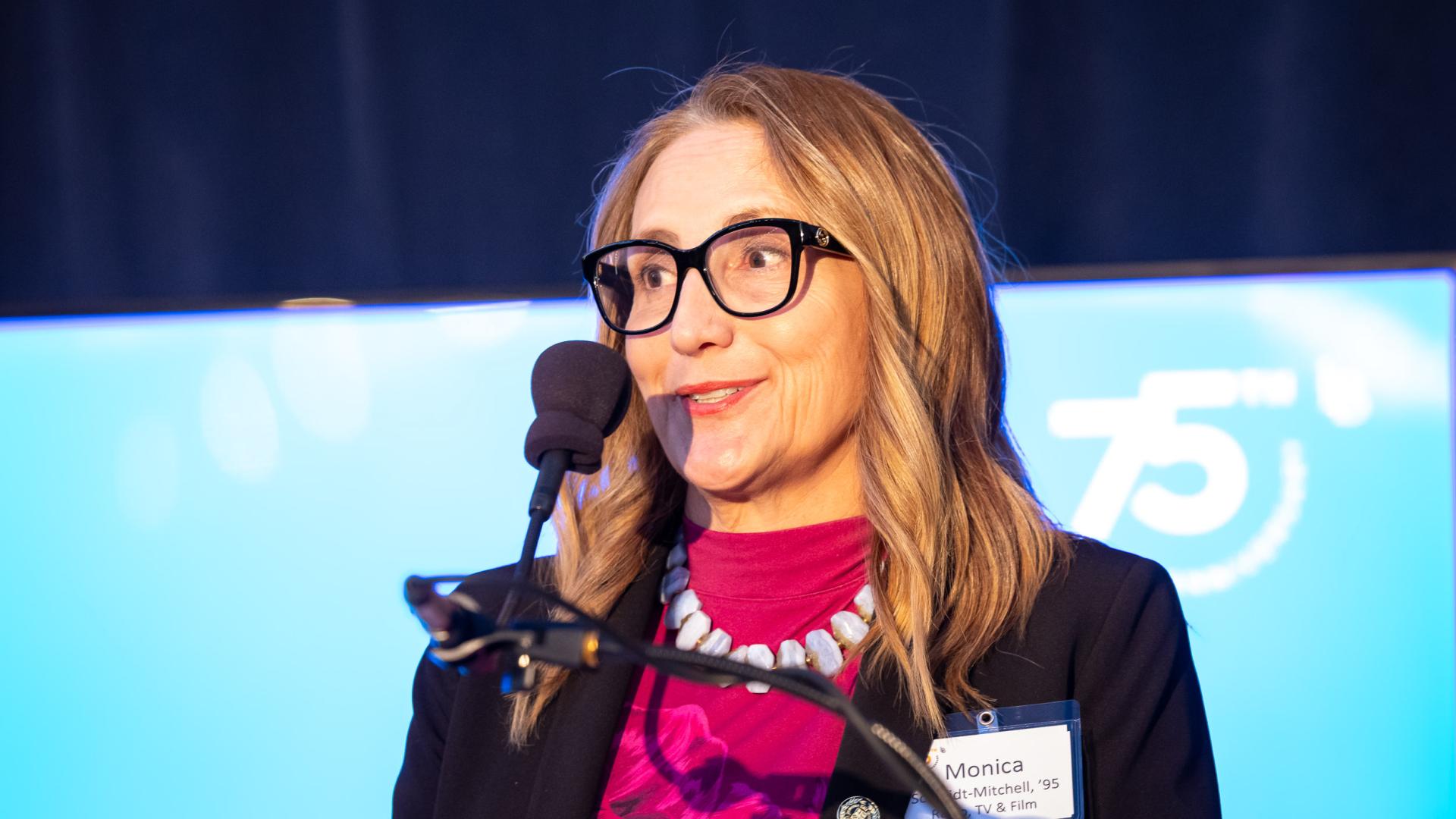 Distinguished Alumni honoree Monica Schmidt-Mitchell standing behind a microphone