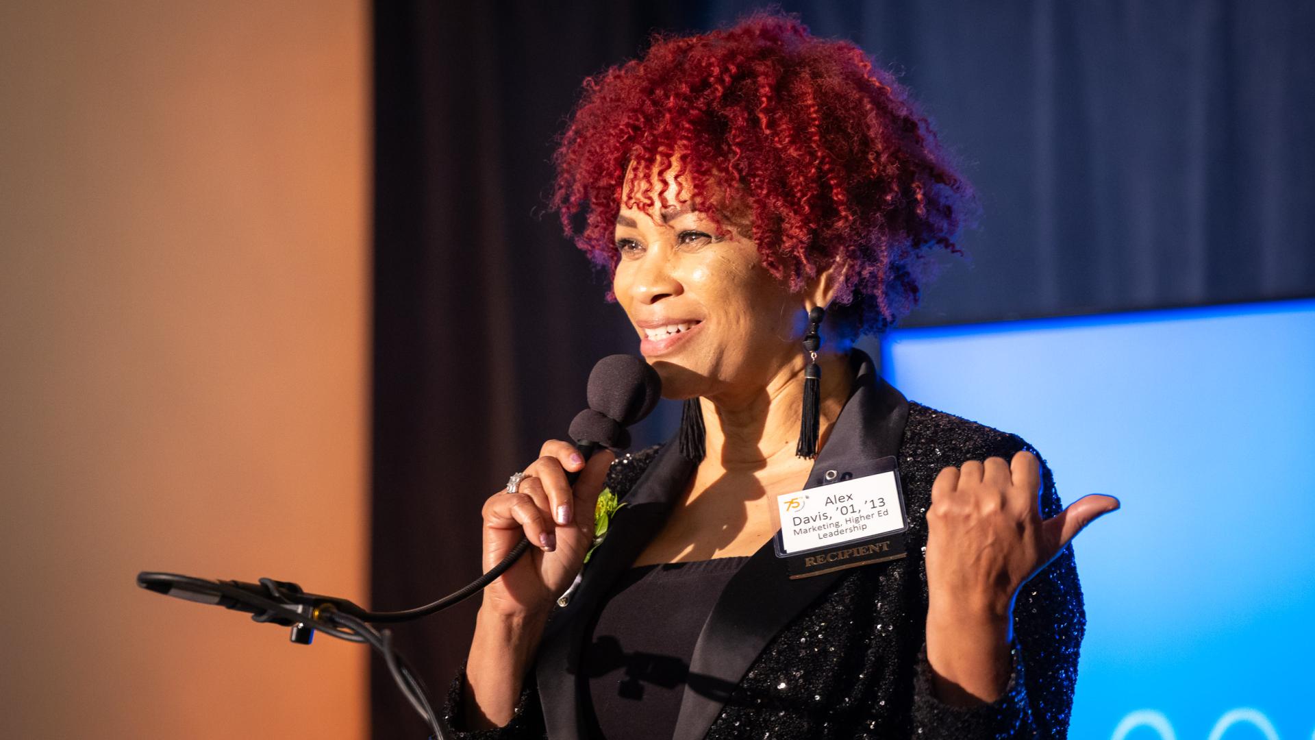 Distinguished Alumni honoree Adriene “Alex” Davis speaks while holding a microphone