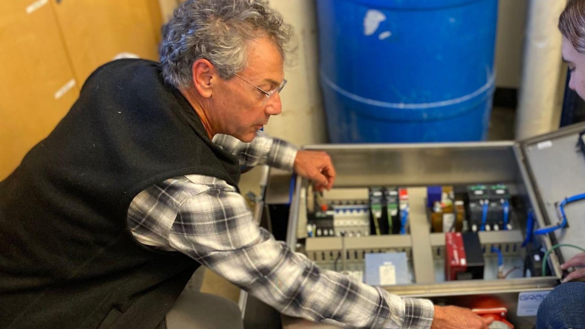 A man leans over lab equipment