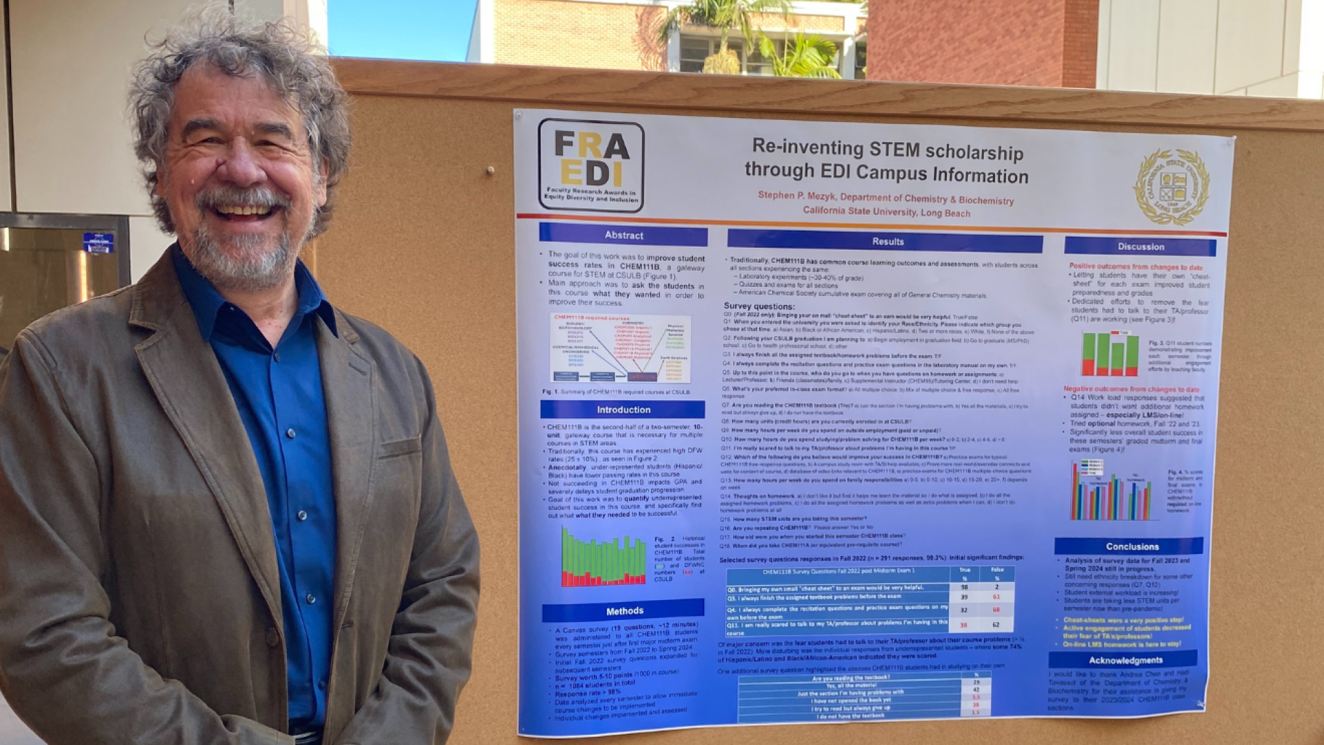 A man stands next to a poster that says "Re-inventing STEM scholarship throught EDI Campus Information"
