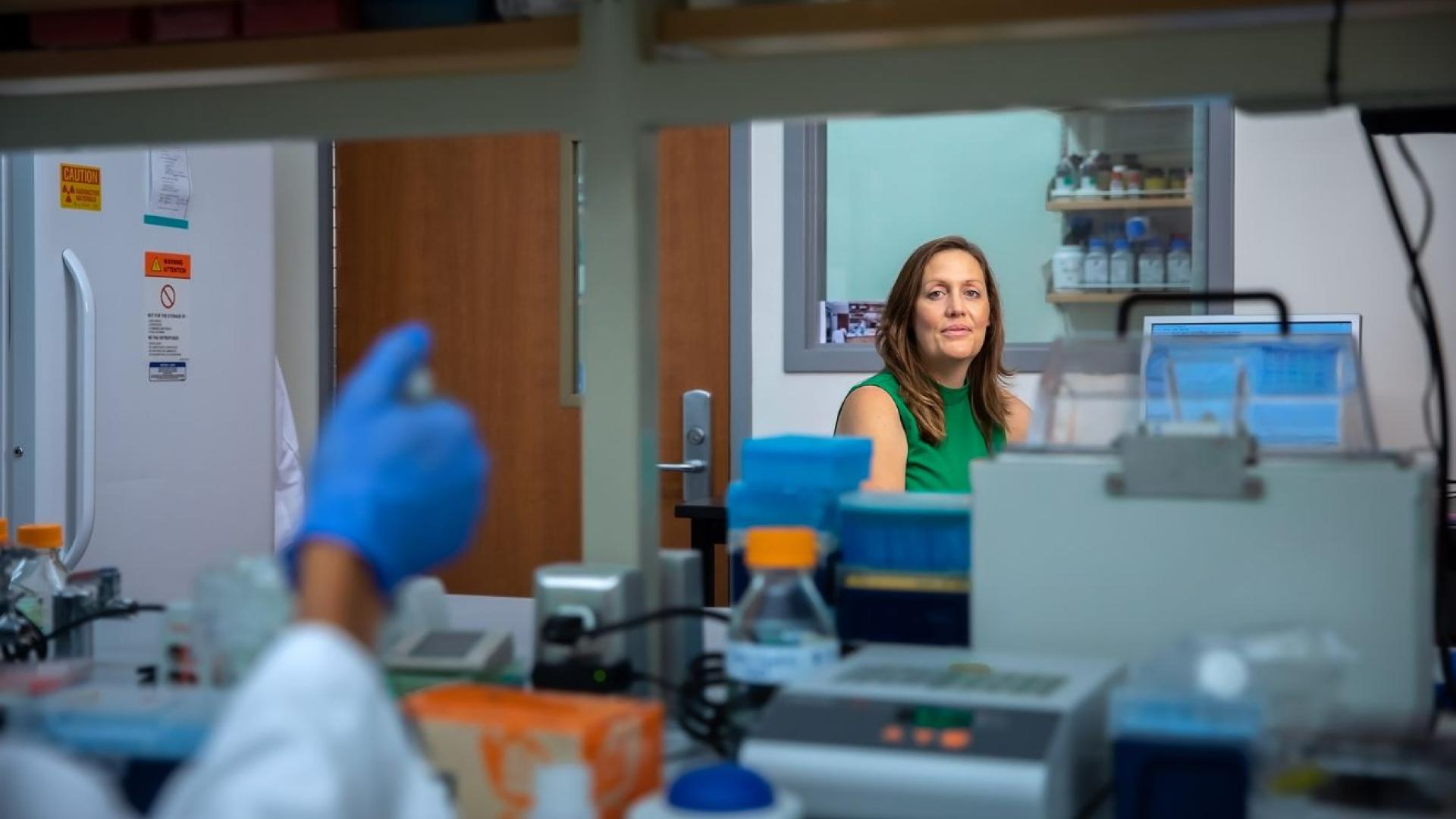 A woman in an office is photographed through a lab window