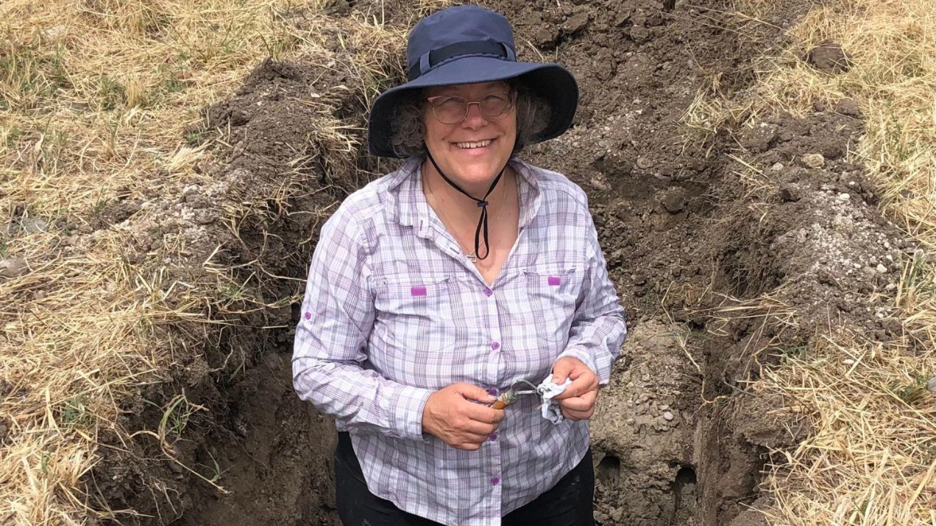 A woman in a sunhat poses in a ditch