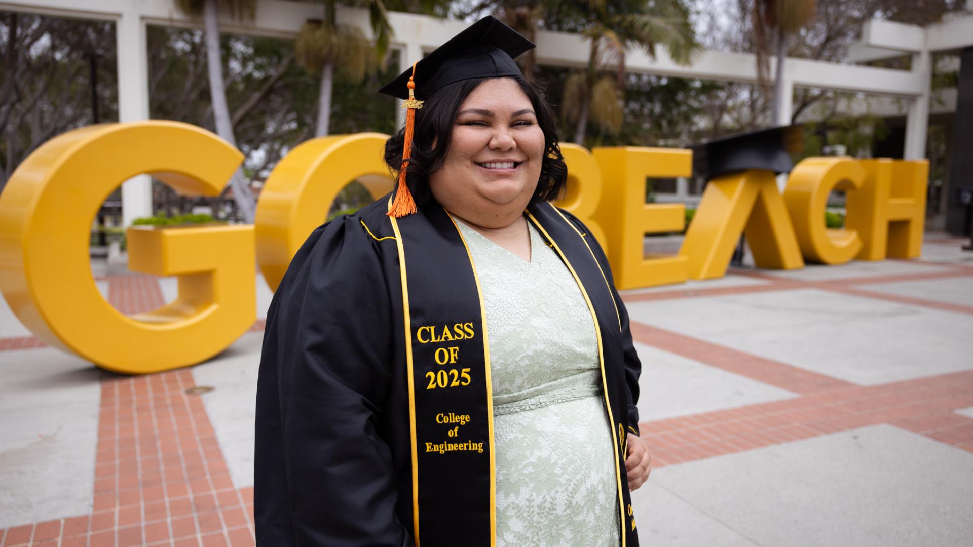Student standing in front of the go beach letters