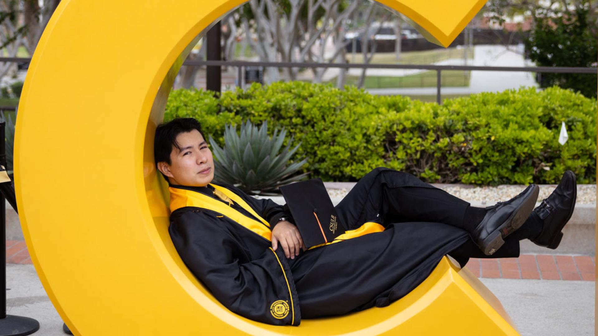 student sitting in the letter C of the Go Beach sign