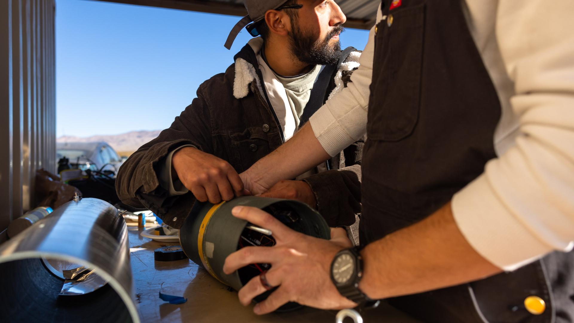CSULB students work together on a rocket component at a bench