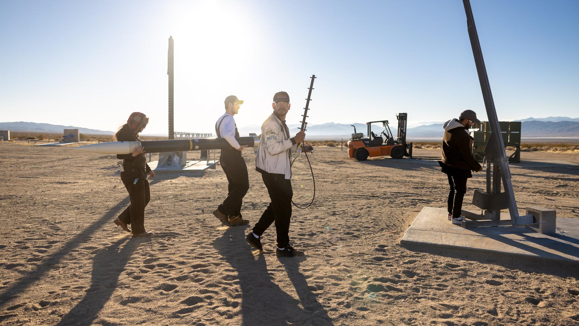 Students carrying a rocket and equipment to test site