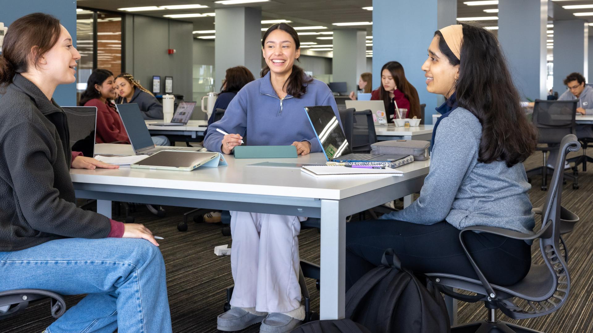 Group of students seated at a table at the library.