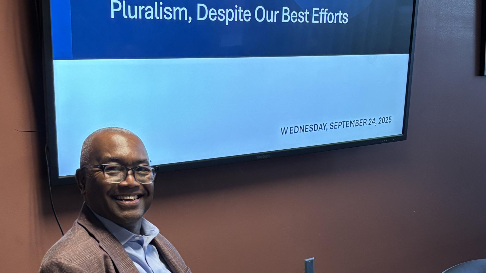 man in front of screen with title of talk