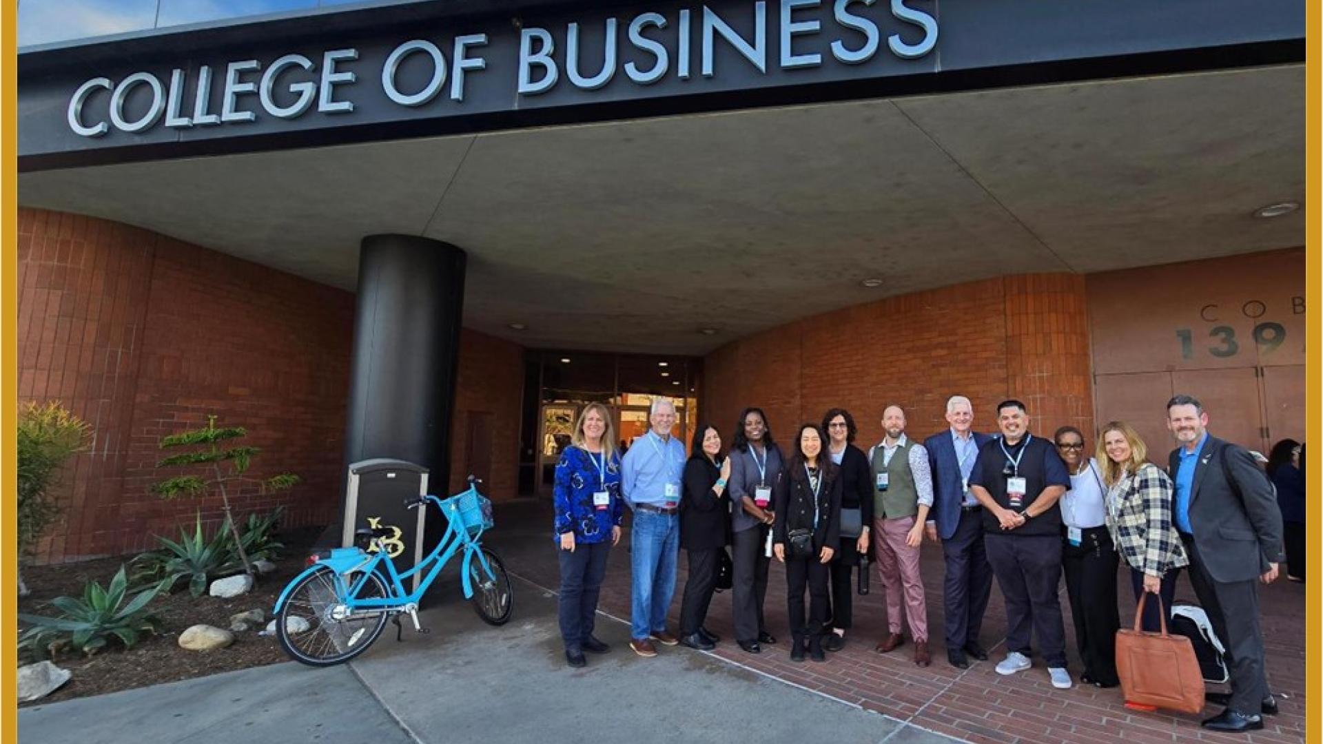planning group and come of the volunteers who organized the HR Symposium, taken in front of the “College of Business” sign
