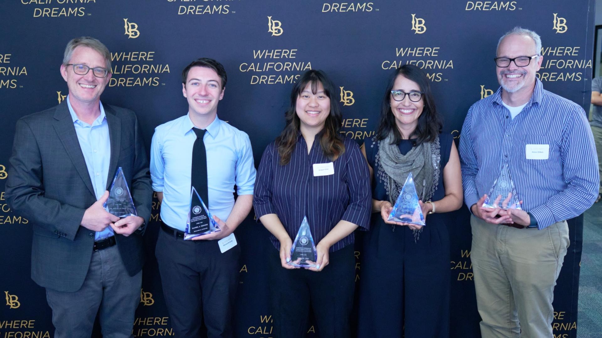 Group of University Achievement Award recipients with their trophy.