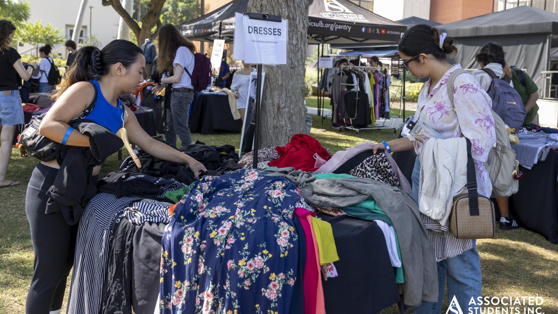 Two students looking through a pile of dresses