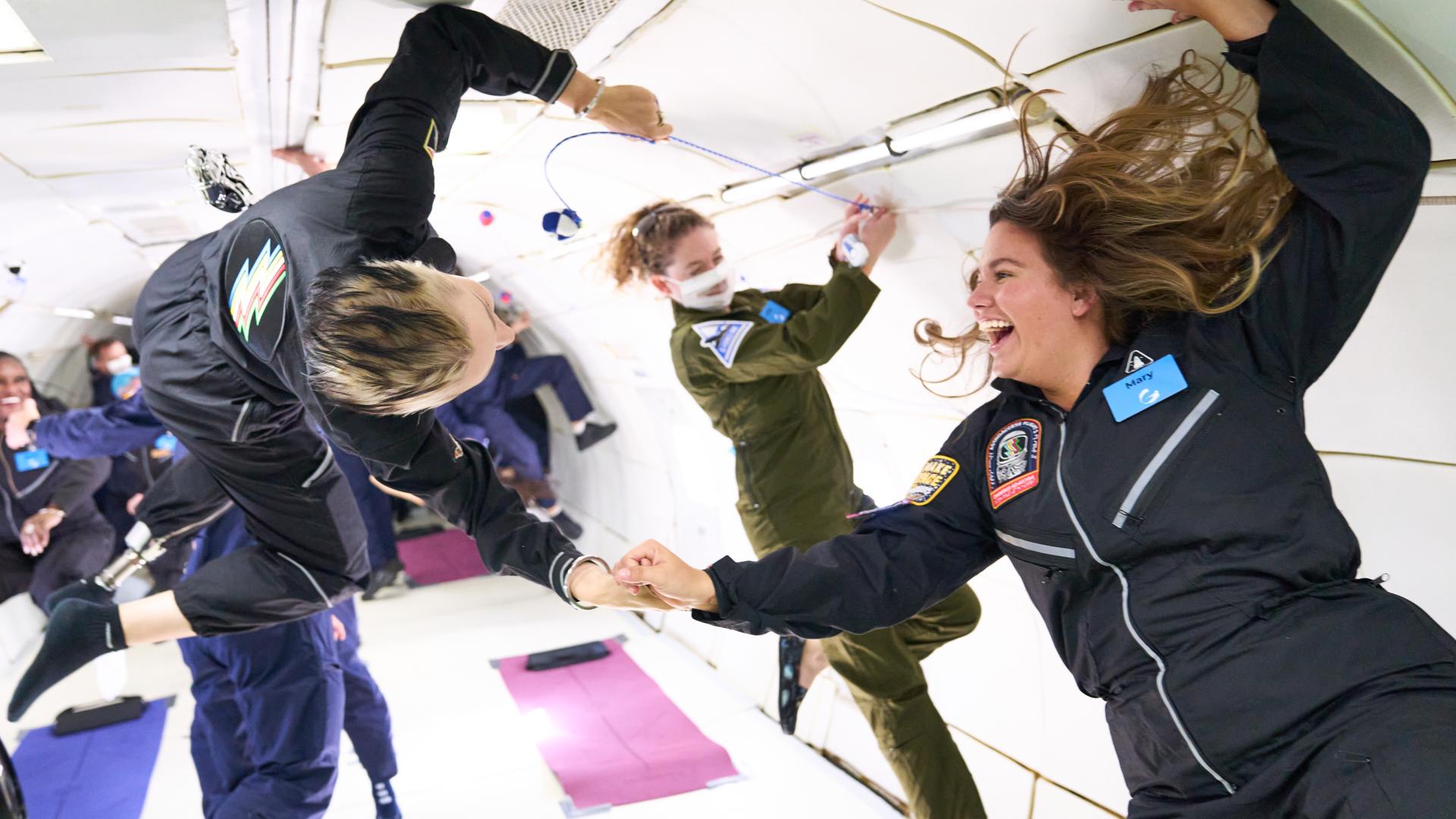 Woman laughs and holds hand with fellow space crew member (Photo: AstroAccess)