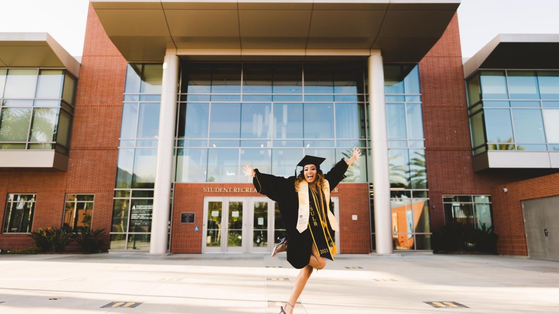 Gloria jumping in front of SWRC in cap and gown 