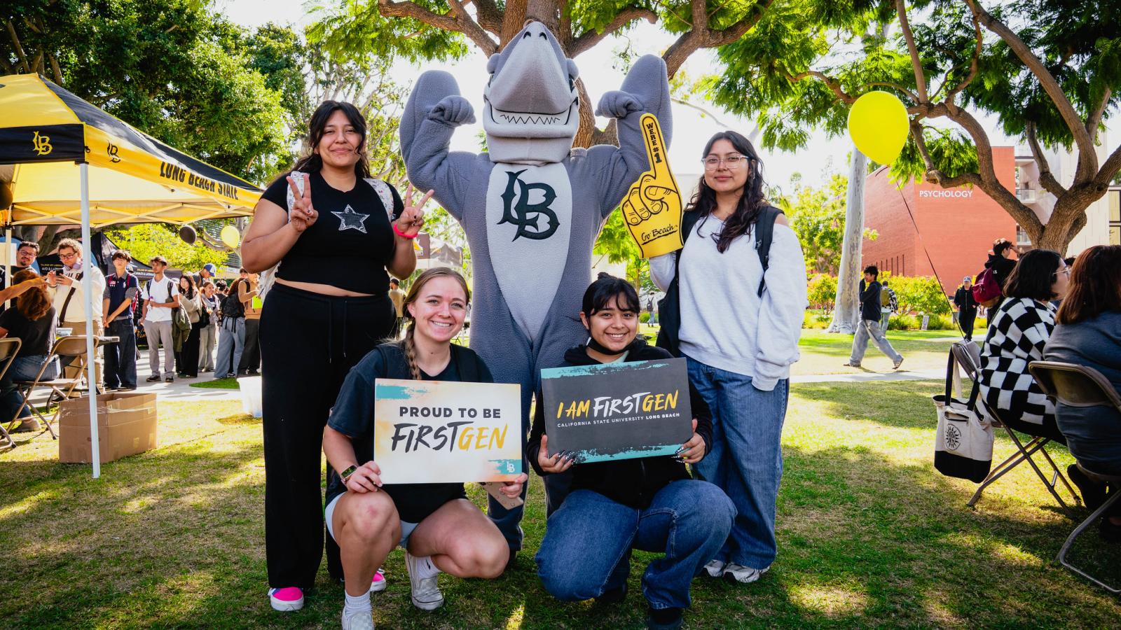 Group of four students celebrating FirstGen celebration with Elbee the shark.