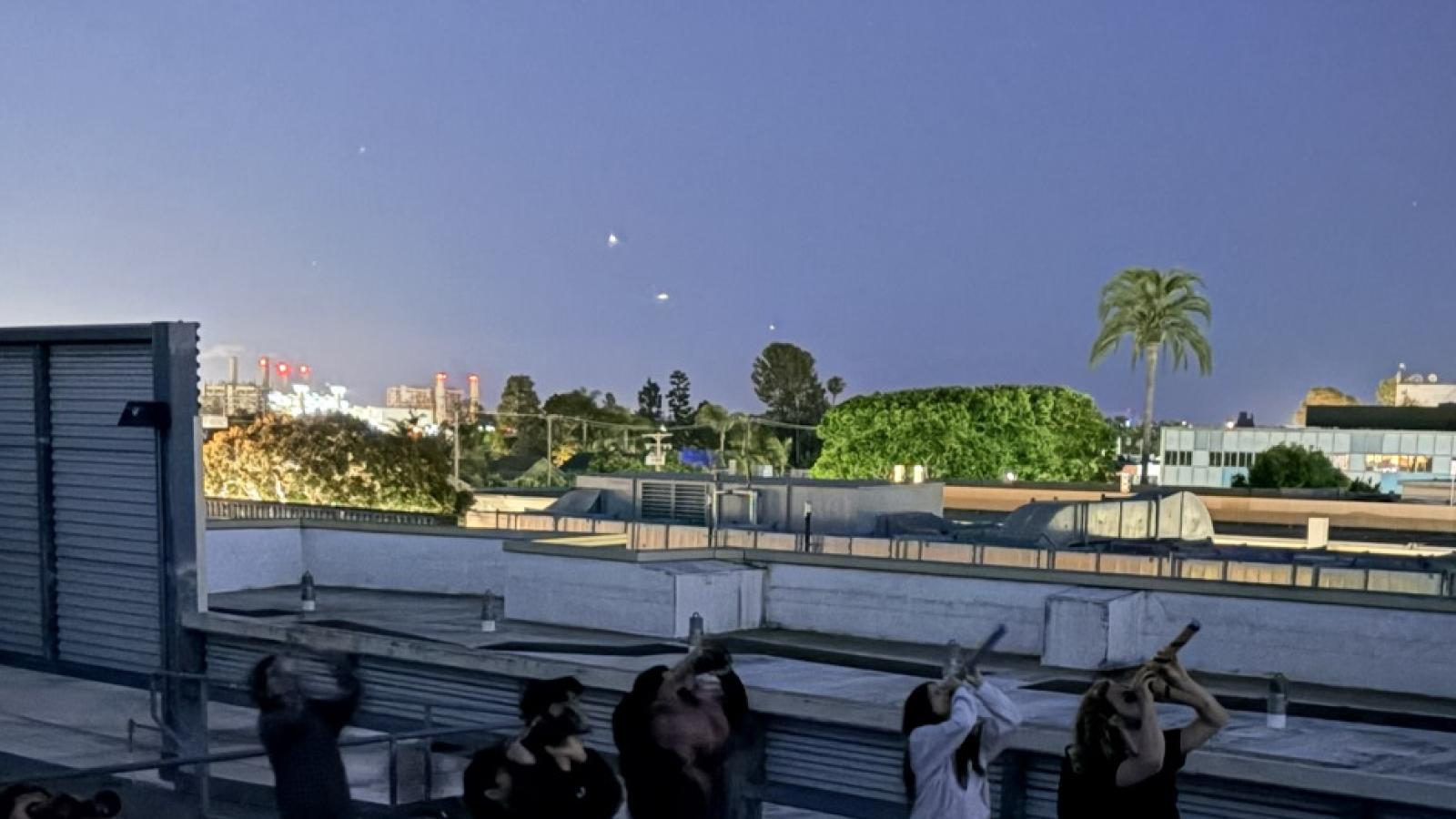 people on rooftop using telescopes to look at night sky