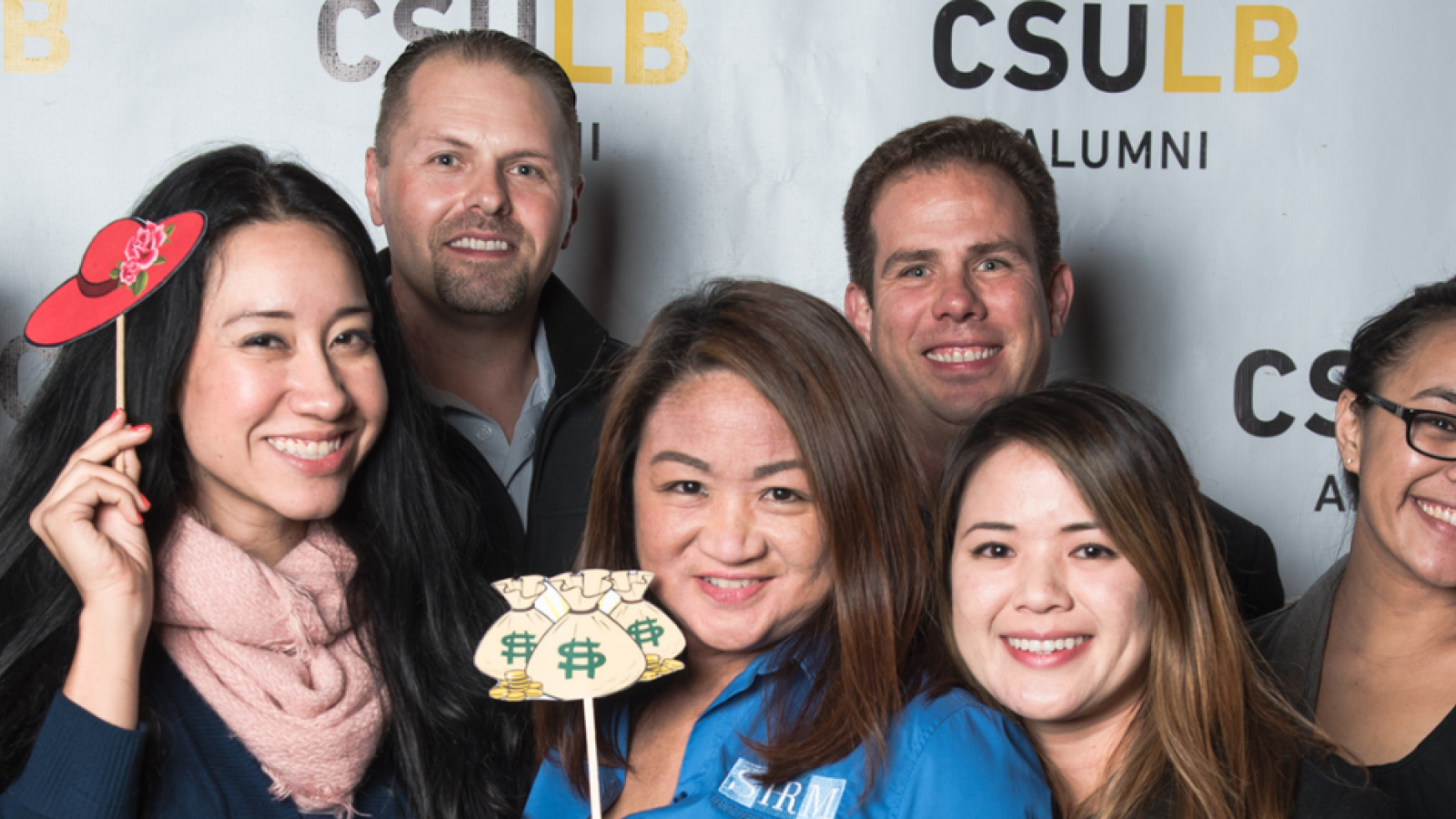 Group of MBA students posing behind a backdrop at an event