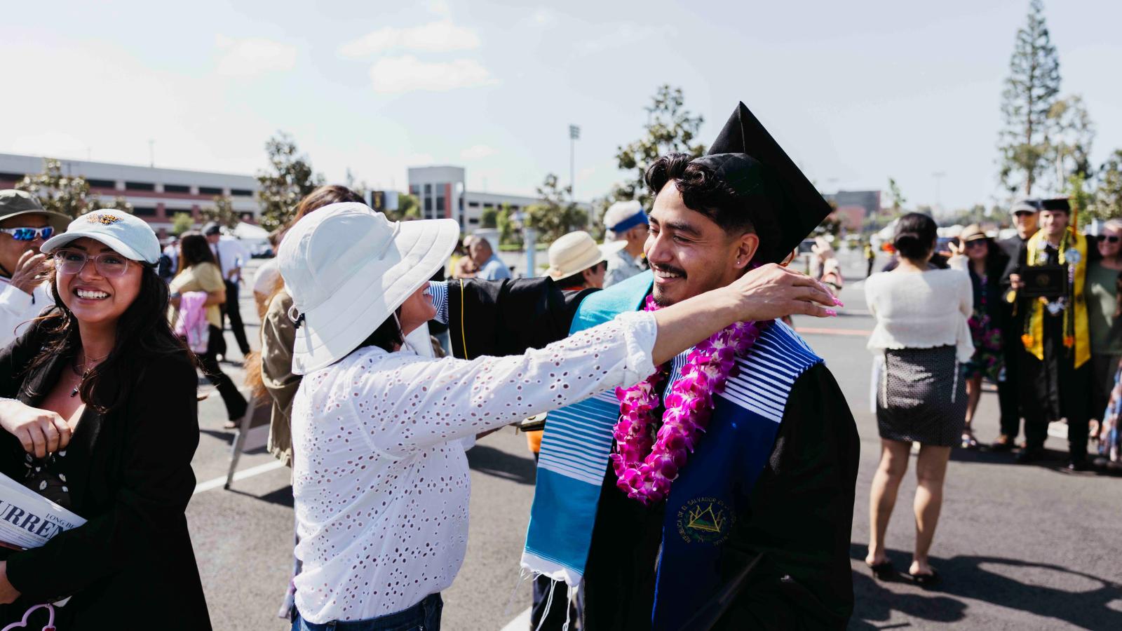 a student graduating going in for a hug with a parent