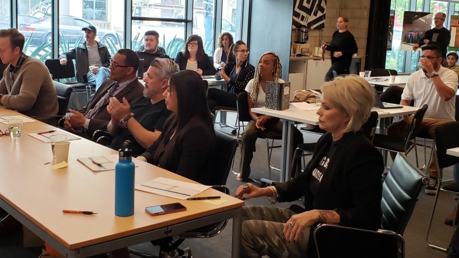 diverse group of people sitting all looking at the front of the room