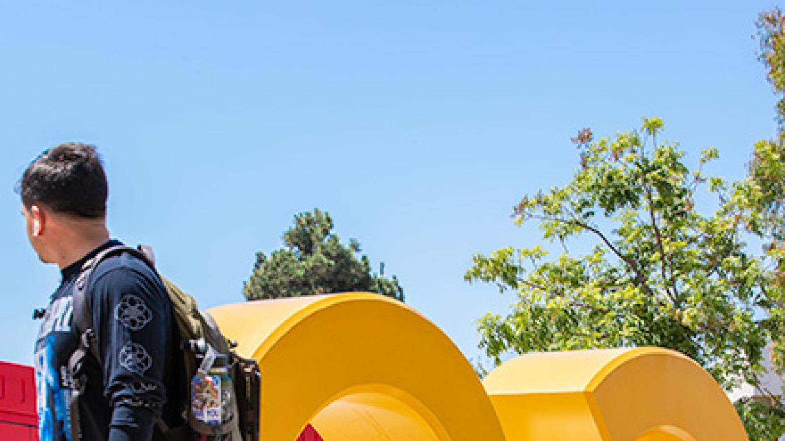 Students walk by the GO BEACH letters