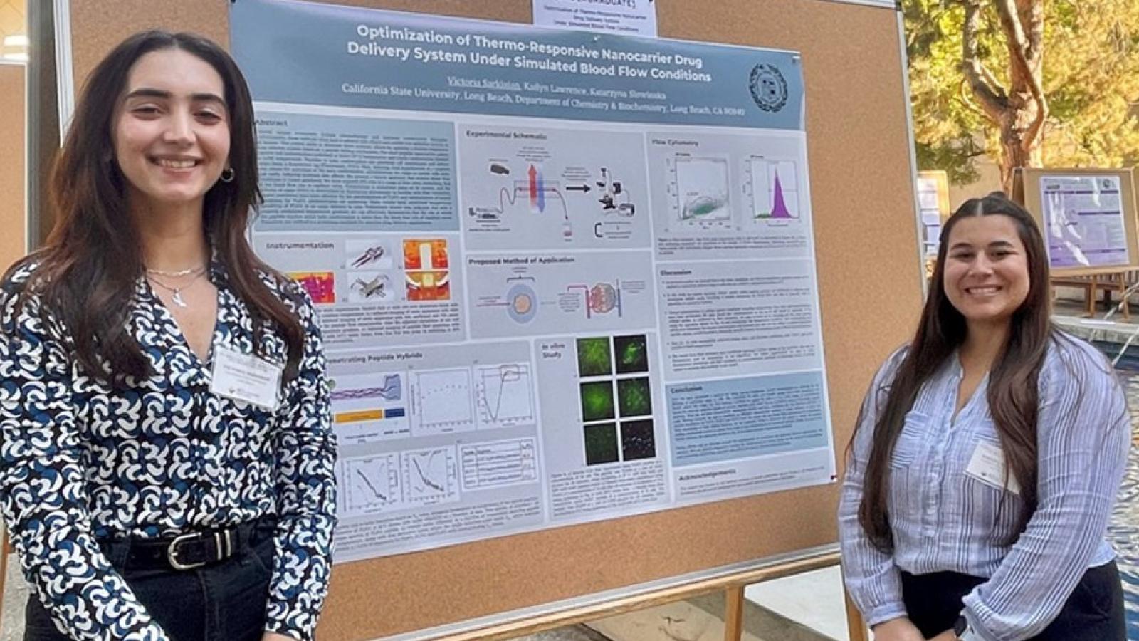 two chemistry students standing proudly in front of their poster presentation