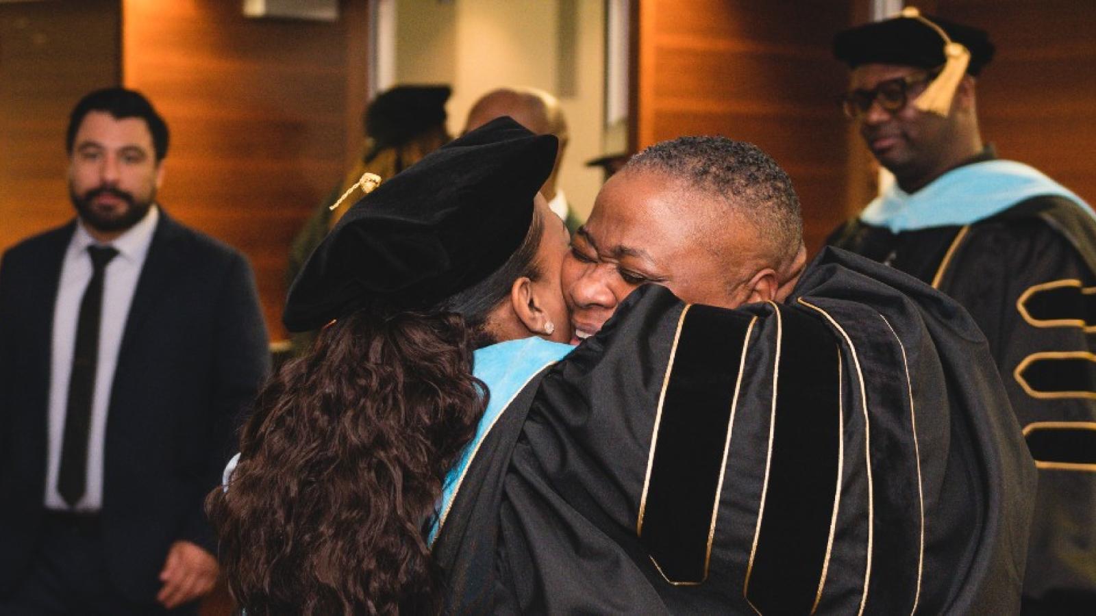 Two people hug at an Educational Leadership Doctorate Hooding Ceremony.