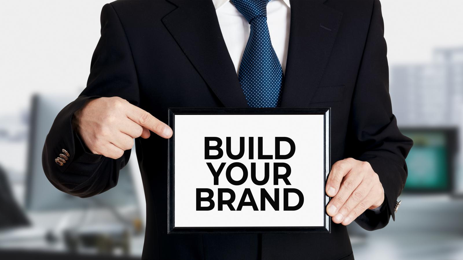Man holding Sign saying : build your brand