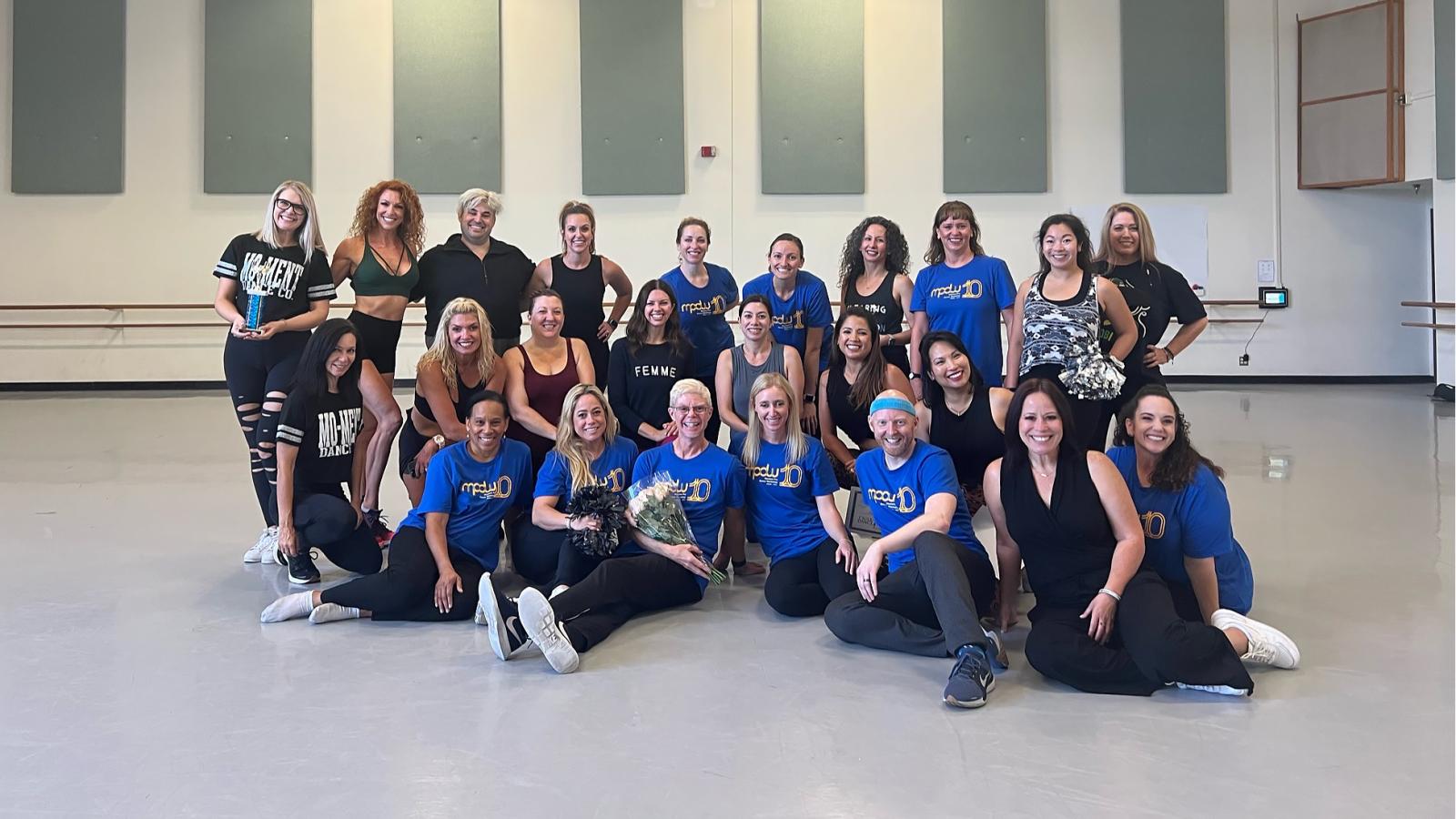 MPDW participants and teachers in a group pose within a dance studio.