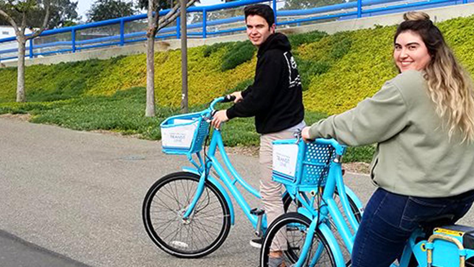 Two students riding on blue bikes