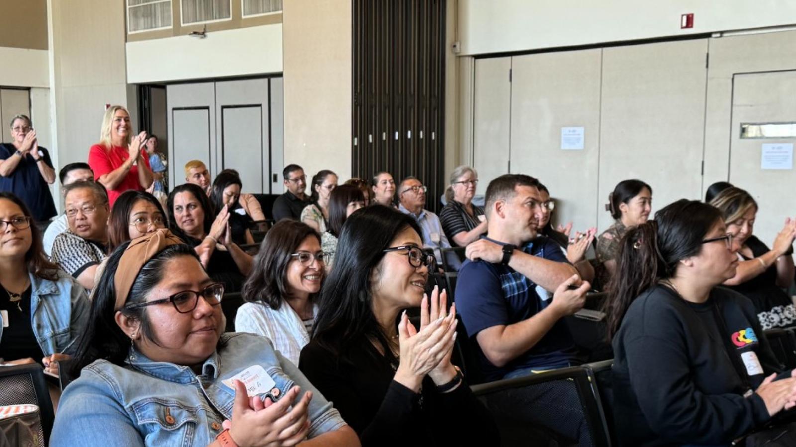 An audience claps after hearing a speech delivered.