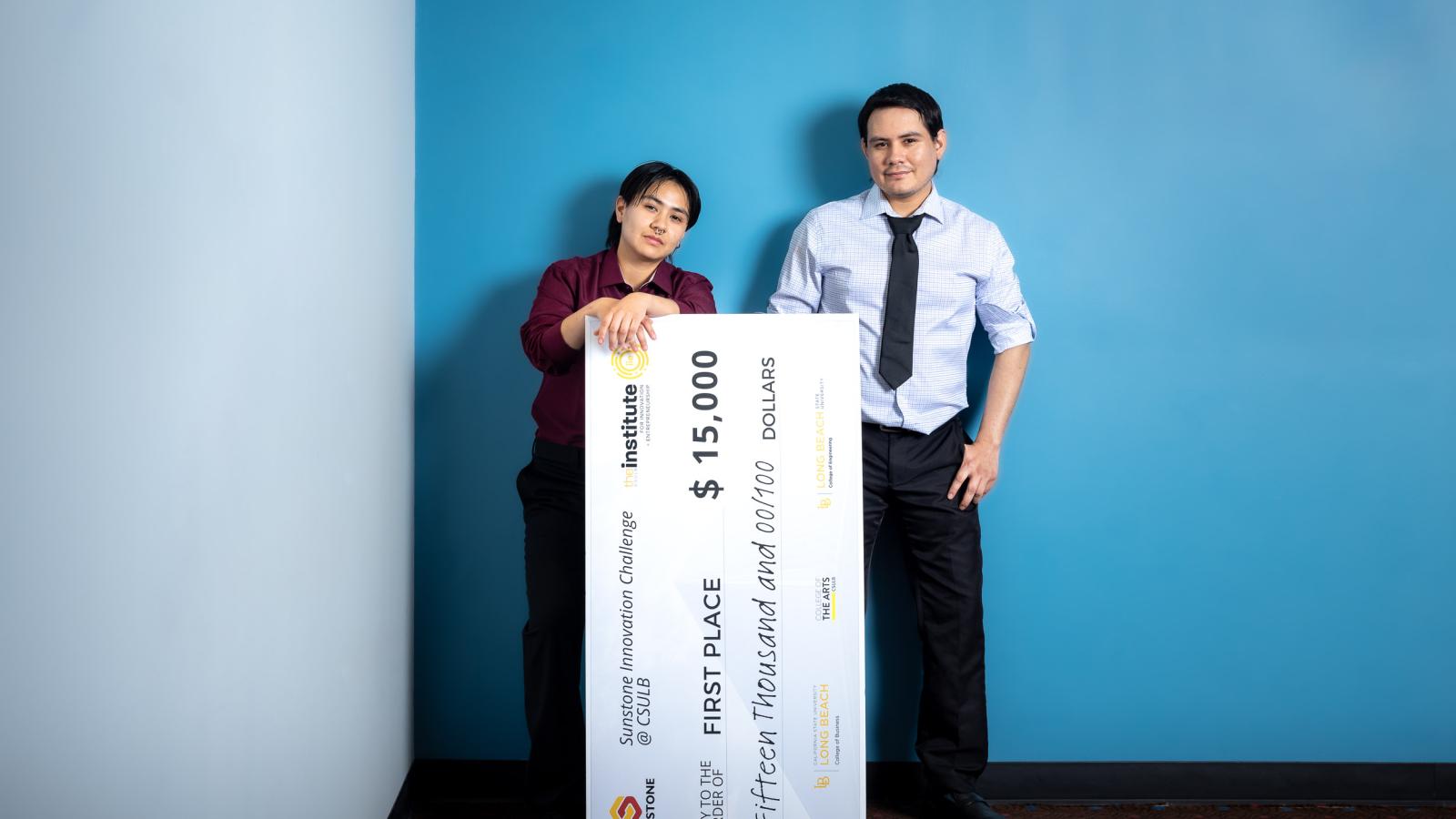 two people standing in front of jumbo check for $15,000