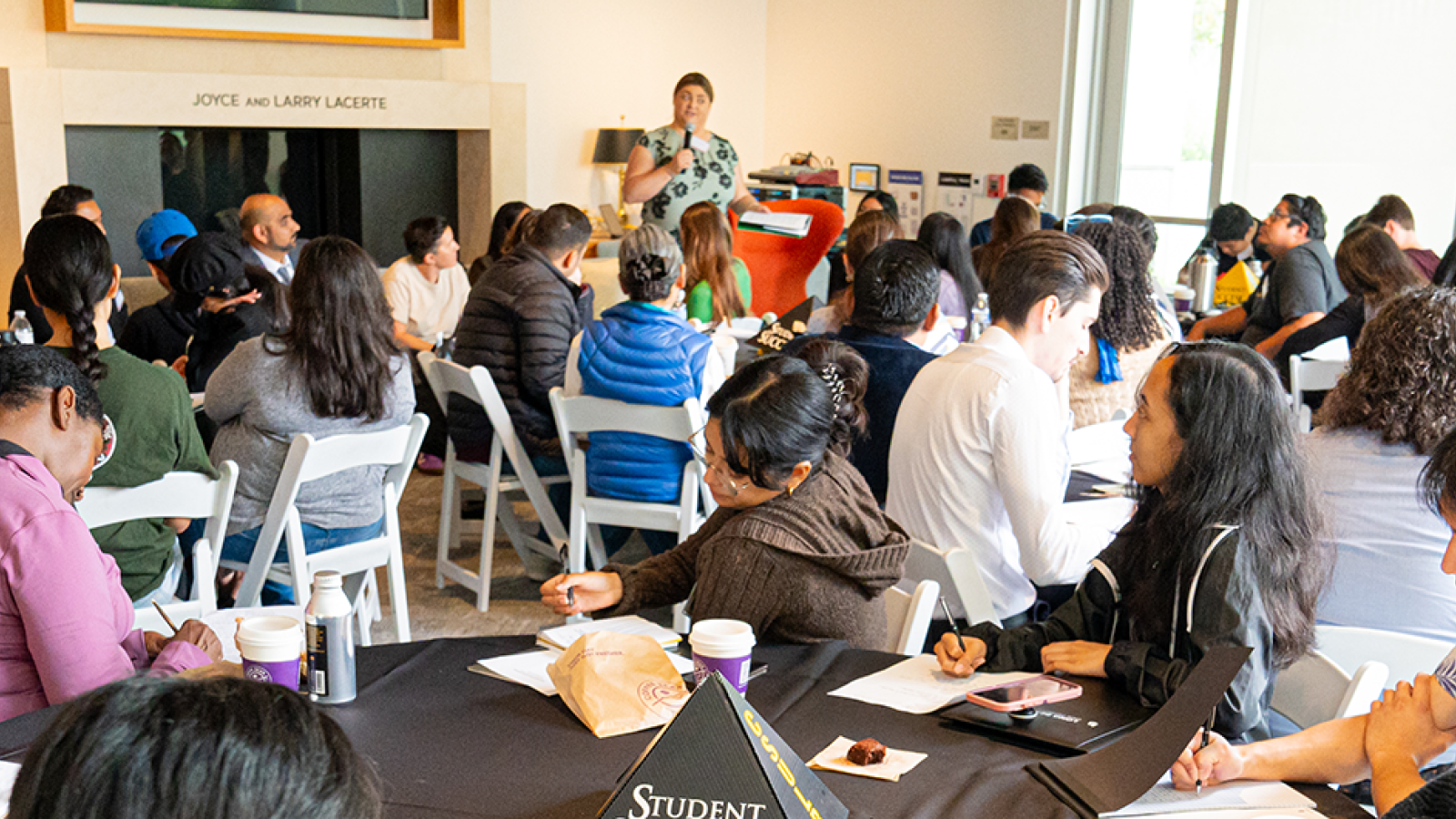 Students attending a workshop, with a speaker presenting at the front of the room
