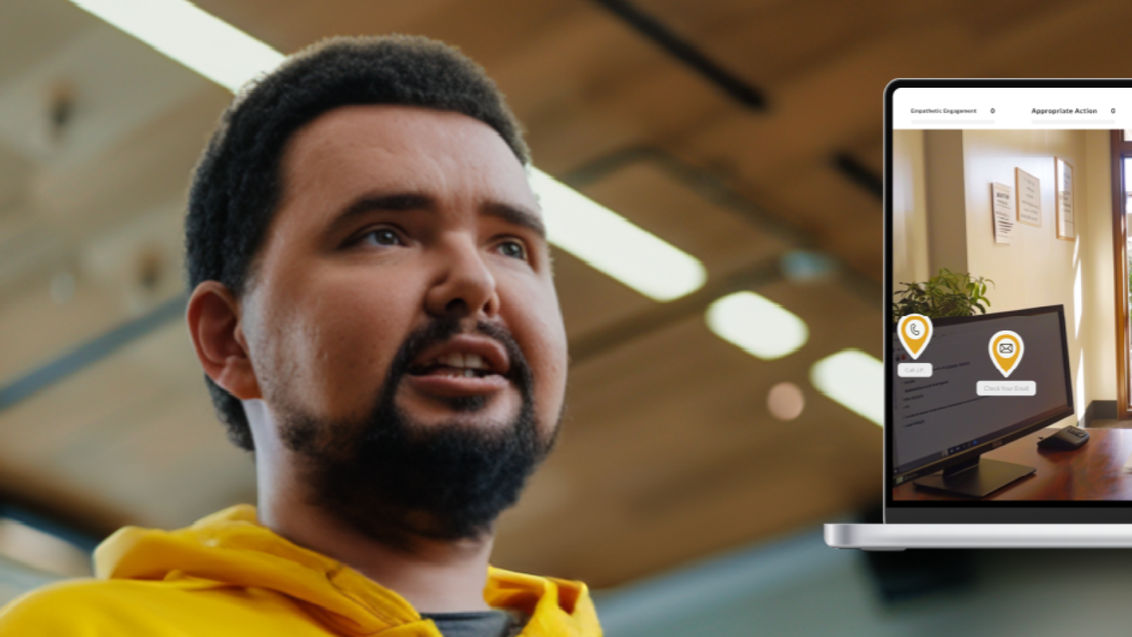person in a yellow hoodie in a classroom with a computer with a simulation game on it
