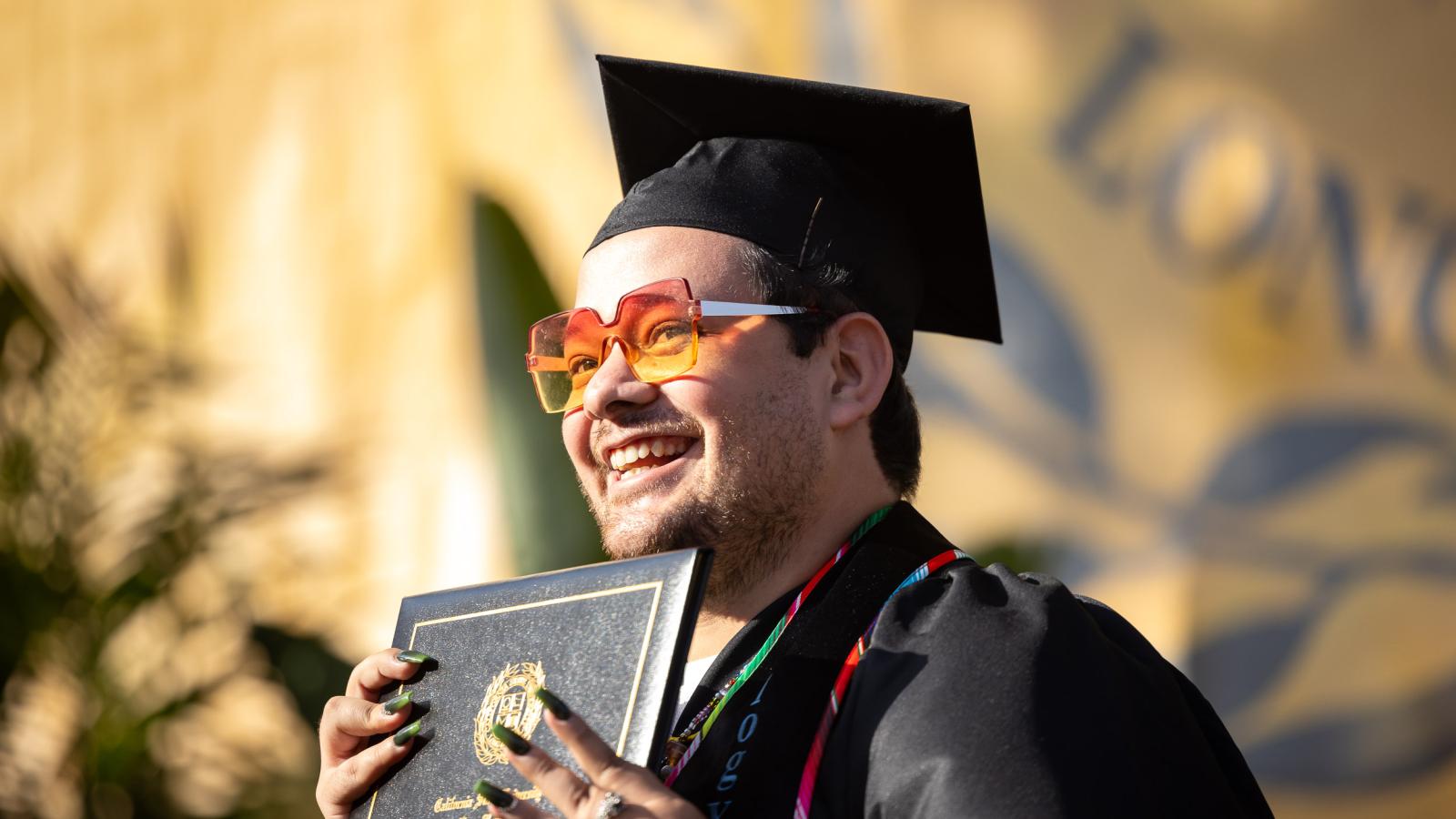 College of the Arts Graduate holding up their diploma