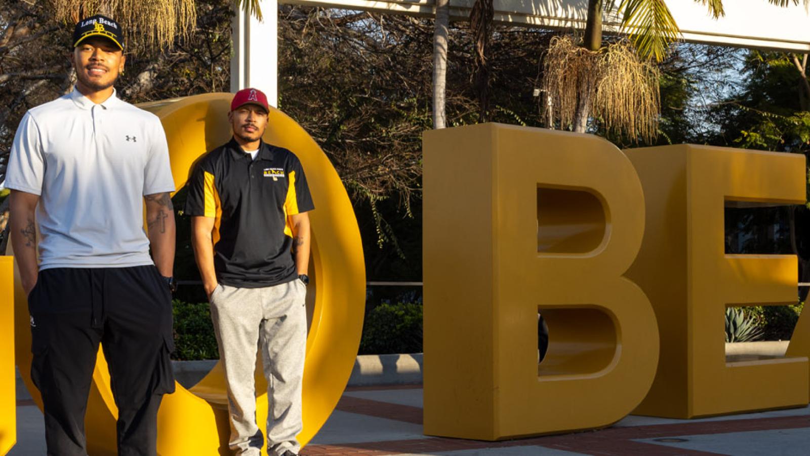New banner image of Markel and Martel Cooper '19 in front of GO BEACH sign