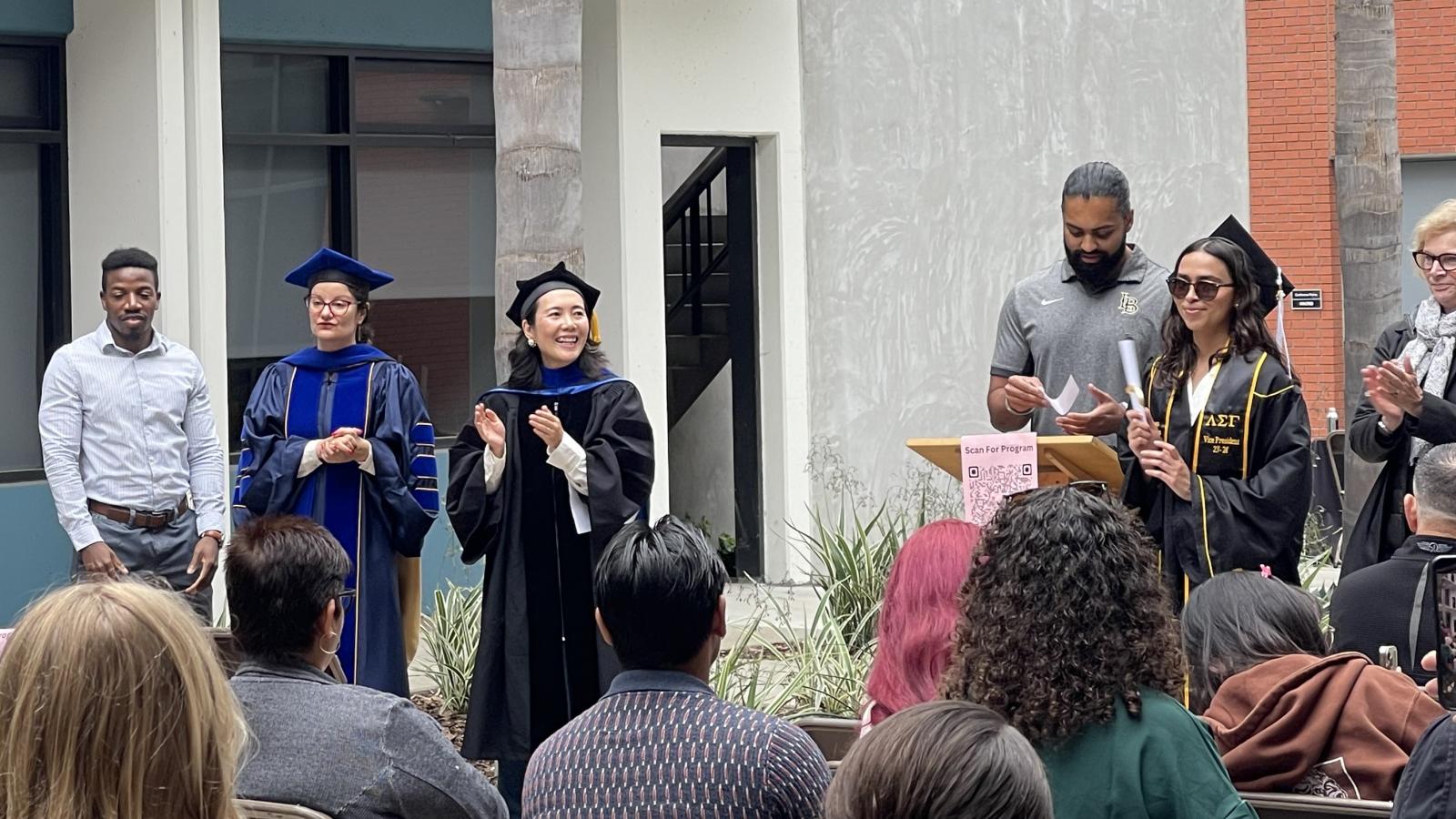 Photograph of a graduating student walking during the procession in front of the faculty, family, and friends. 