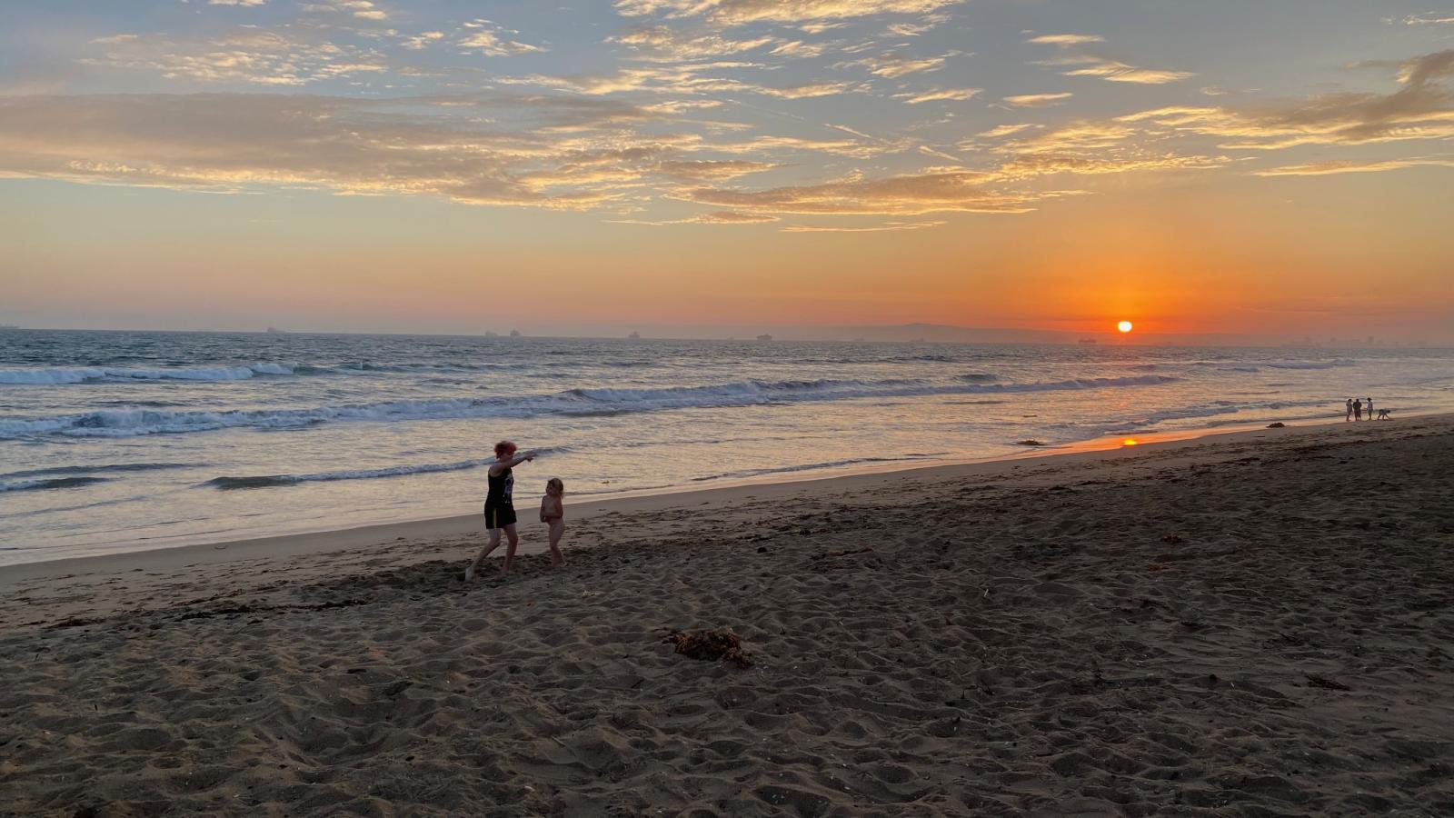 2 people on the beach at sunset