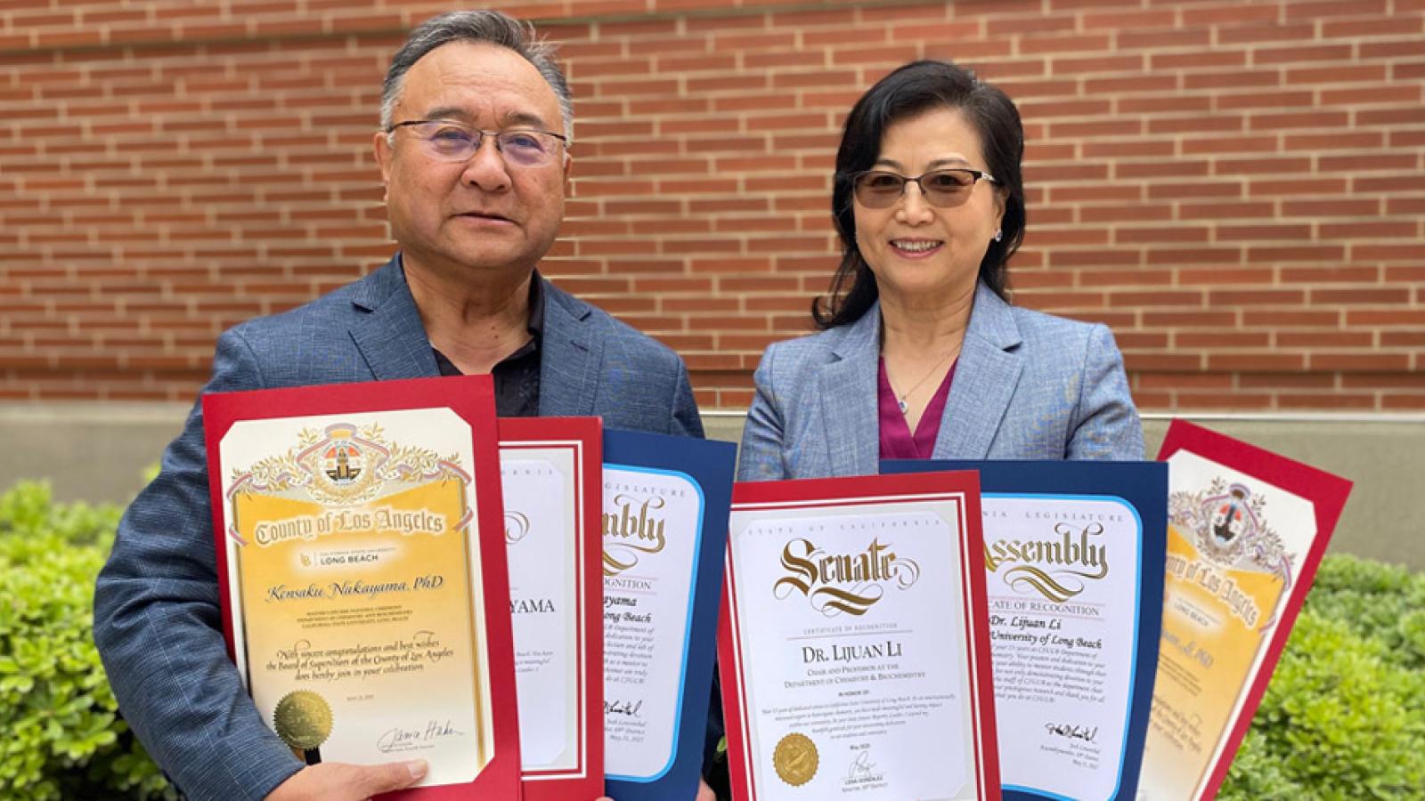Kensaku Nakayama and Lijuan Li holding multiple award certificates
